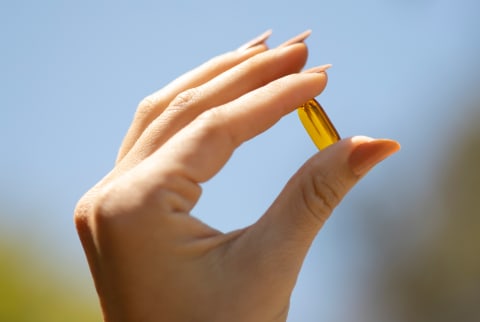 Hand holding mindbodygreen vitamin D3 supplement Hand holding mindbodygreen vitamin D3 supplement