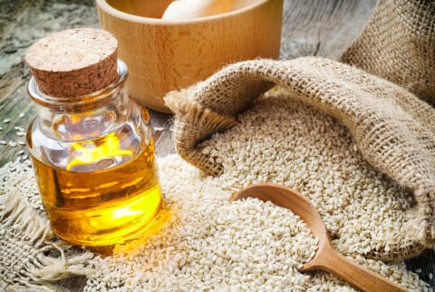 Sesame seeds in sack and bottle of oil on table Sesame seeds in sack and bottle of oil on table